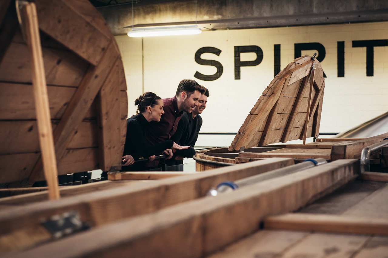 people inspecting whiskey spirit barrel